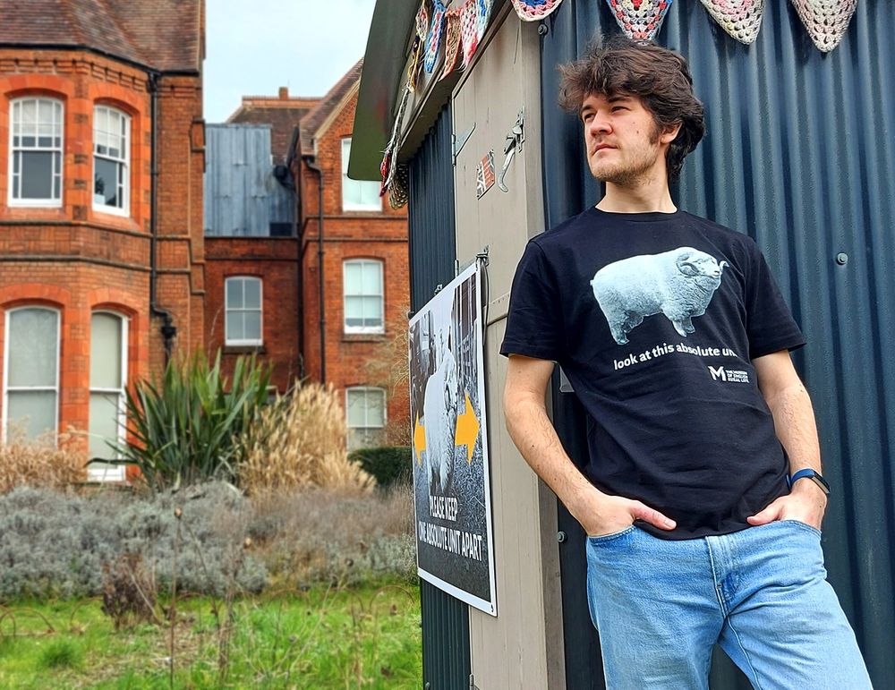 A member of our team wears a 'look at this absolute unit' t-shirt, leant against the shepherd's hut in the Museum garden.