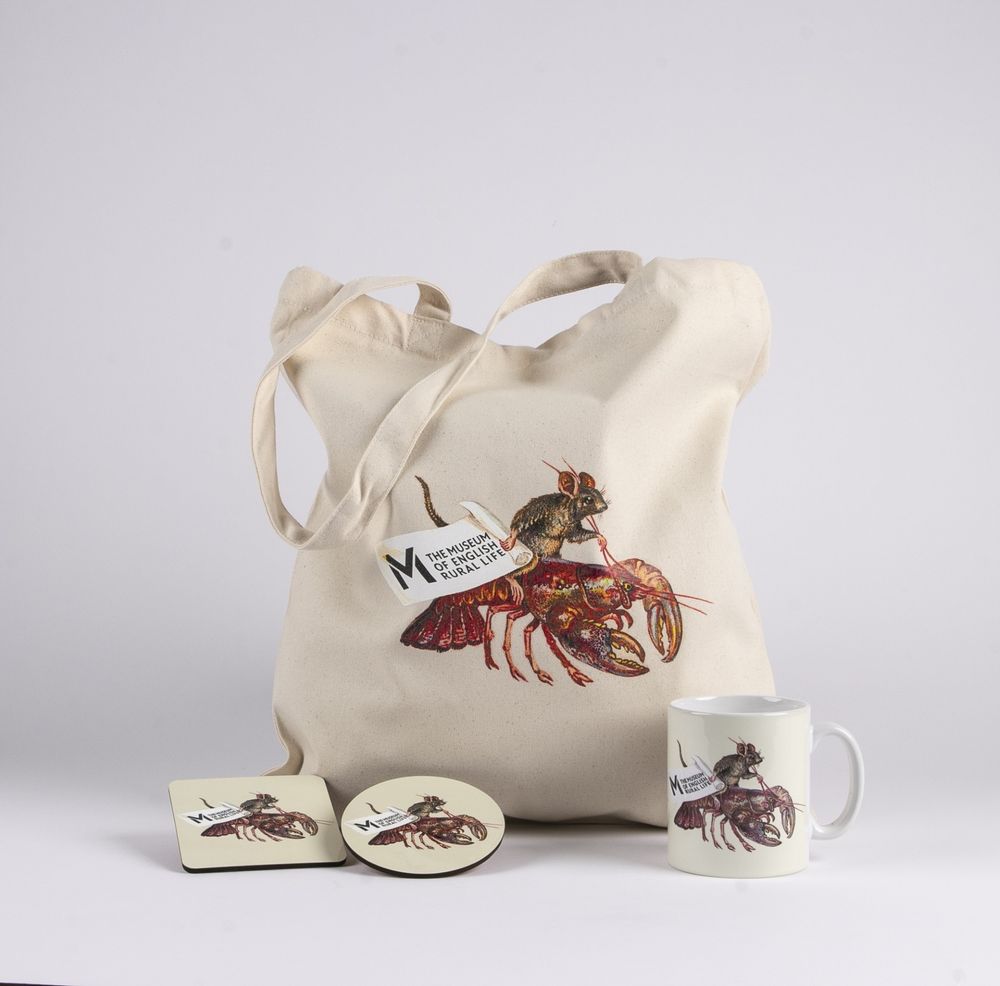 Merch for The Museum of English Rural Life. Each item - a tote bag, a mug, and two coasters - is adorned with an artwork of a mouse riding a lobster, holding a scroll decorated with the device of The Museum of English Rural Life.