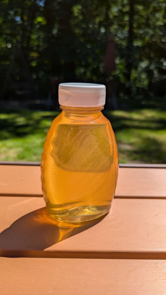 A bottle of honey glistening in the sun