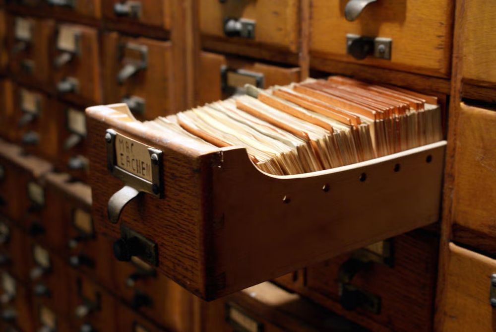 Index cards in a wooden library catalog drawer.
