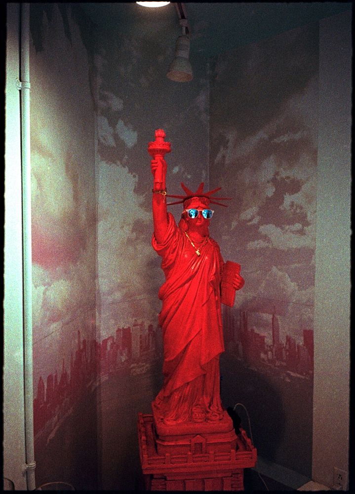 A Statue of Liberty is red and wears mirrored sunglasses.