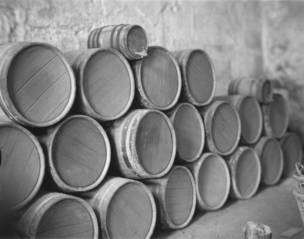 Several wooden wine barrels sit on the floor of a stone fort interior.