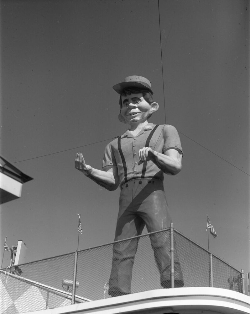 A buff Alfred E. Newman figure stands on a roof.