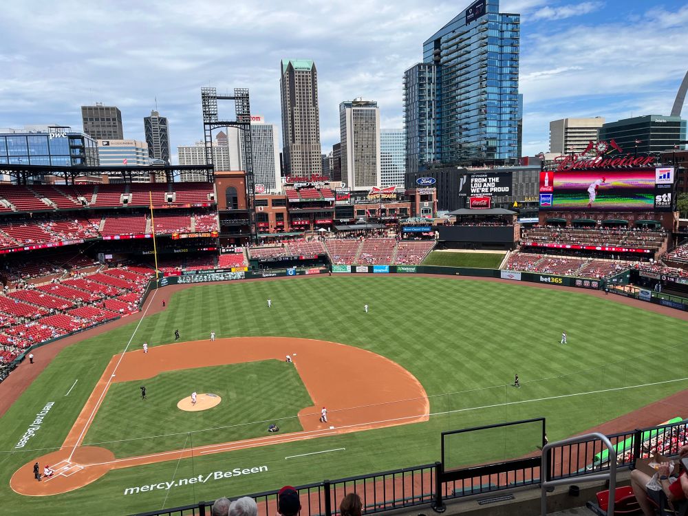 Busch Stadium, home field of the Saint Louis Cardinals, on a stunning false fall Labor Day, 2025. The homeless Athletics are the opponent. View from first base side of the park, high rise, downtown buildings in the near distance.