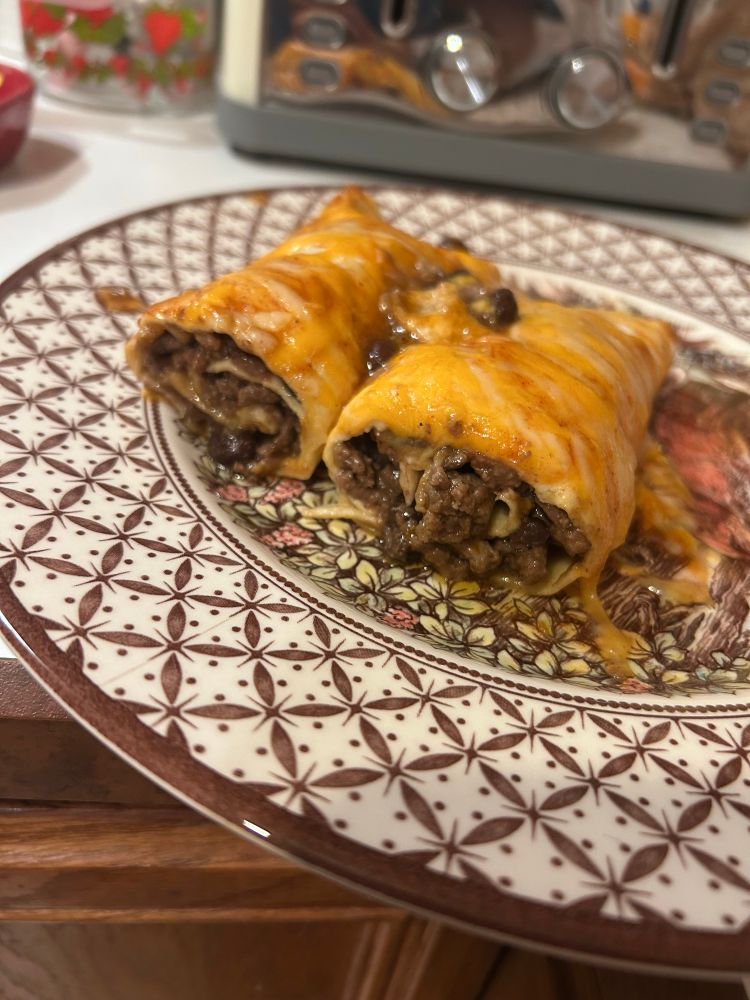 Enchiladas on a plate showing the meat and beans filling