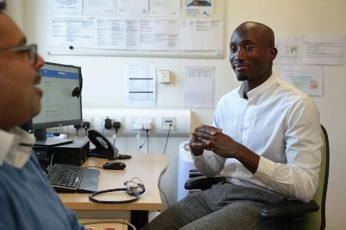 Doctor sitting and talking to patient in office.