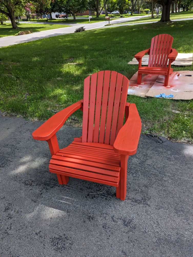 Two adairondak chairs, painted red.