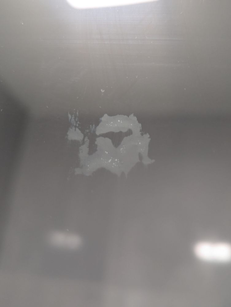A smudge on the window that looks like a frog holding a steaming cup of coffee