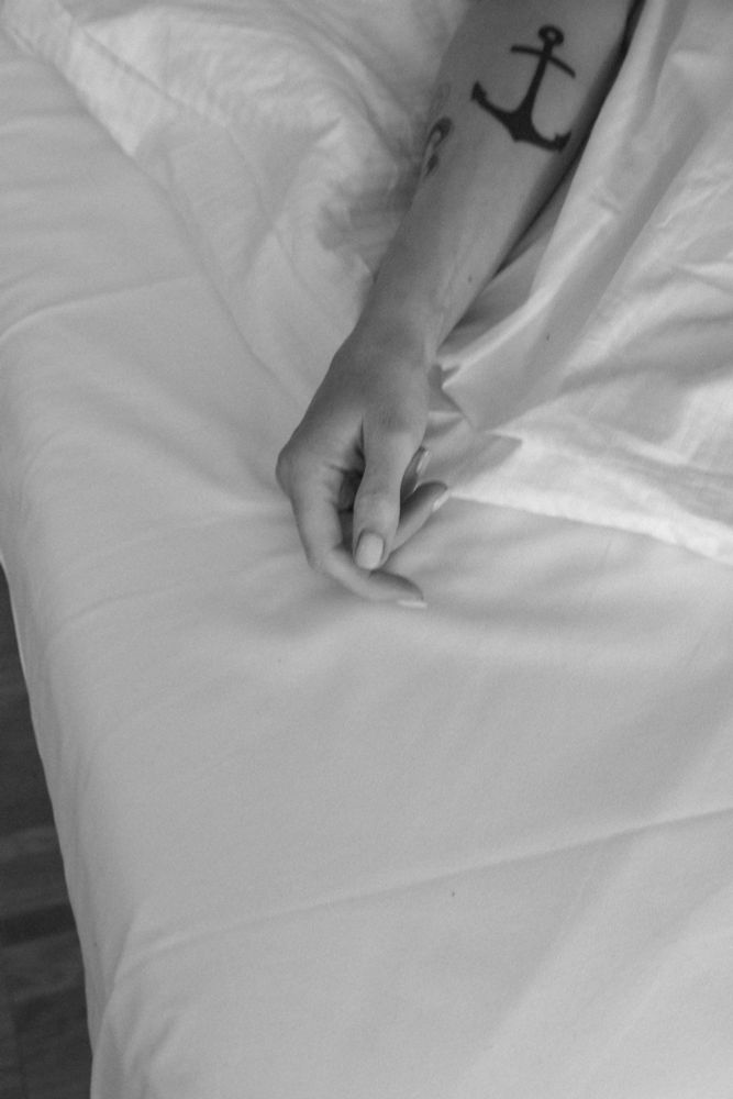 Ausschnitt einer Hand auf einem Bett in schwarz weiß 