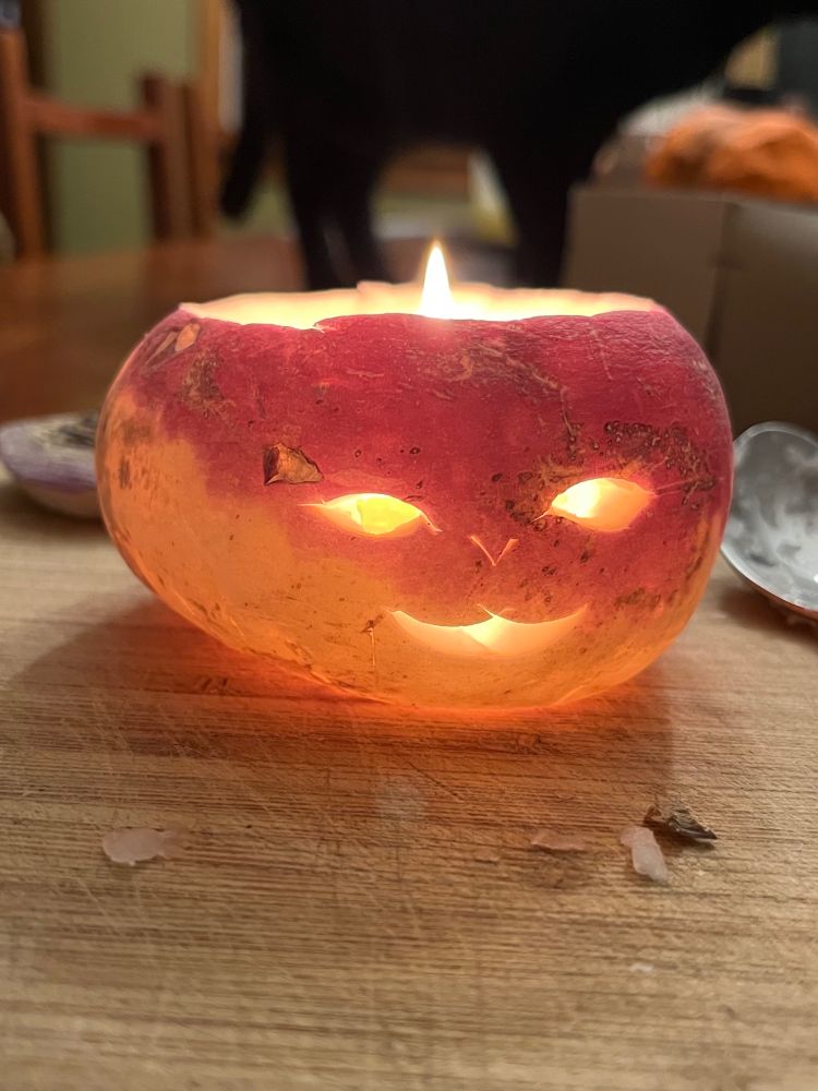 A turnip, I swear it is, but maybe an American one? Because it's shorter than the ones I see in Irish drawings? Carved into a face, and OK it's not a spooky face but rather maybe a forest sprite? Or a cat? It's illuminated from within by a candle, which might have been the wrong way to do it? I honestly don't know. I did use a spoon, and it was quite difficult to hollow out but wow did that face end up cute rather than spooky