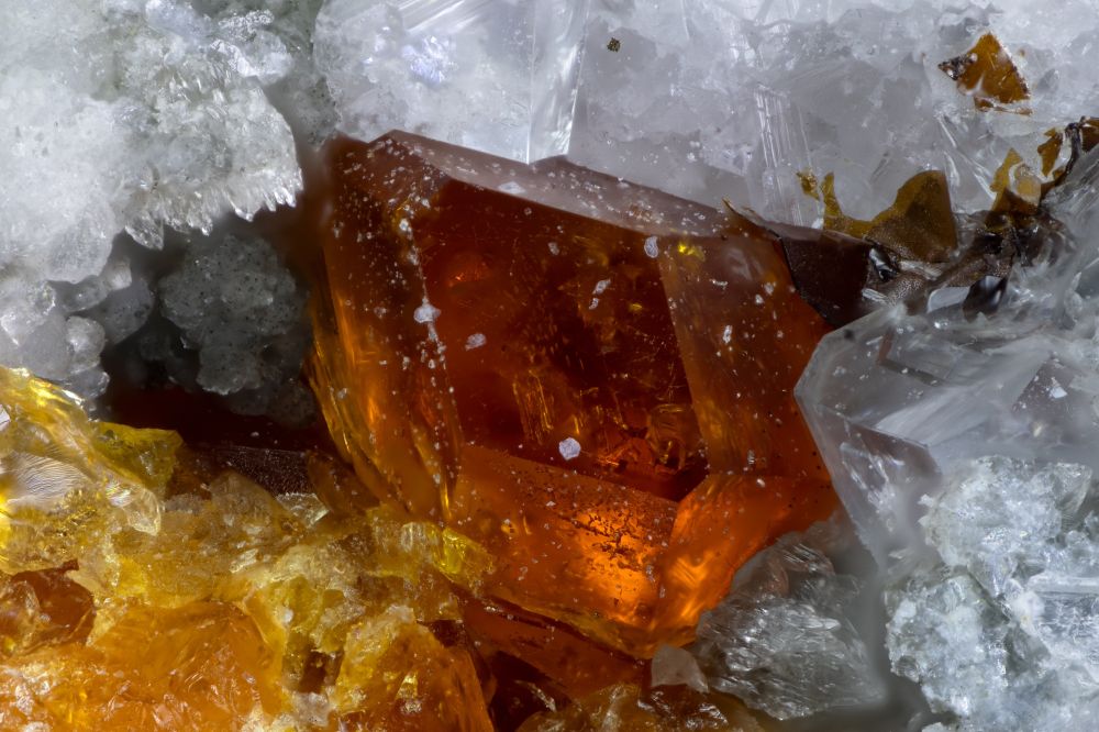 Orange ferrokentbrooksite crystal at center of image in a white to colorless feldspar matrix. The orange mass at lower left is also ferrokentsbrookite. The Poudrette Quarry is the type locality for ferrokentbrooksite and this specimen is from the type lot used for description of the species. It is member of the eudialyte group. 