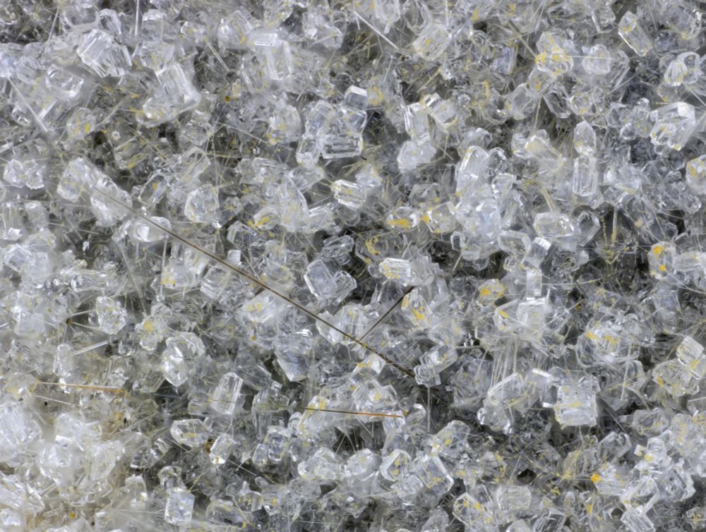 Colorless blocky clinoptilolite-Ca crystals on fine acicular crystals colorless erionite-K crystals The 3 pyrite crystals are the darker crystals radiating from the lower center of the image.