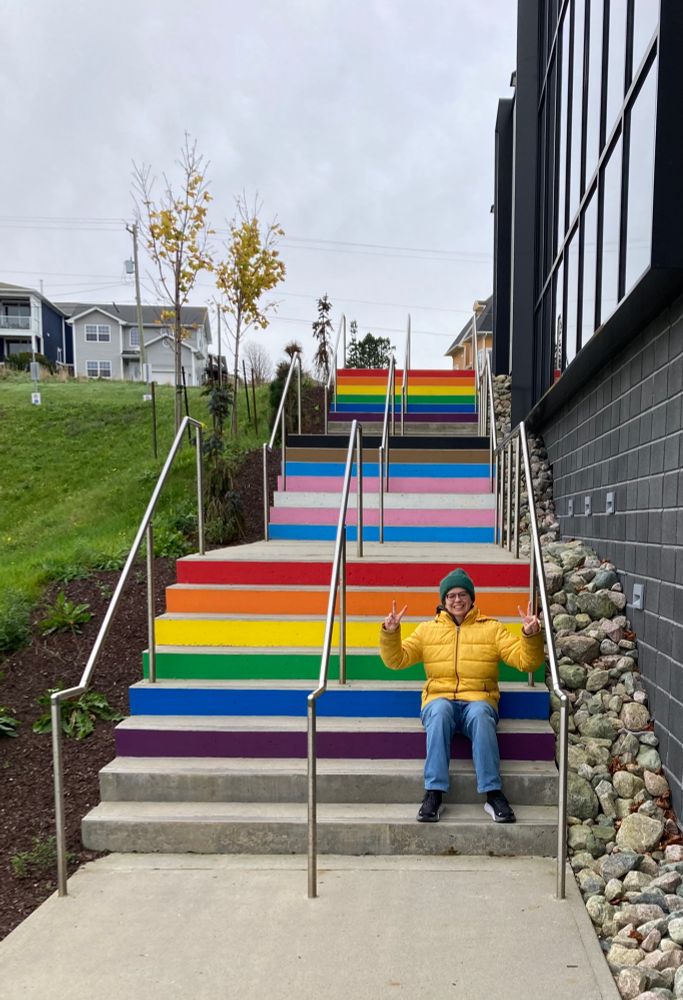 Sam sitting on rainbow stairs in St. John’s, Newfoundland 