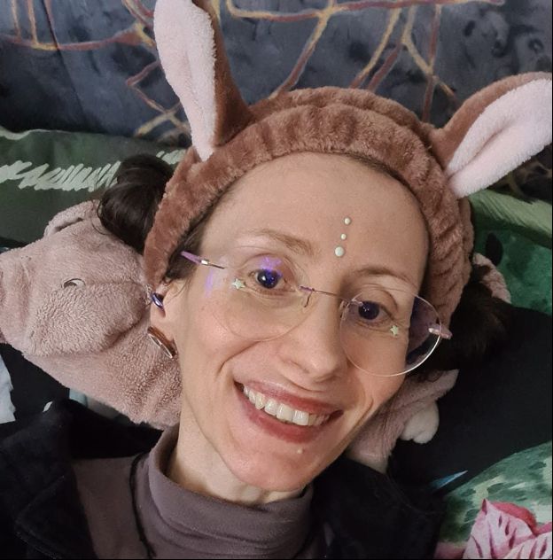 image de Judith avec un serre-tête en forme d’oreilles de lapin…des étoiles sur ses lunettes et 3 points verticaux sur le front. Elle sourit malgré tout…
