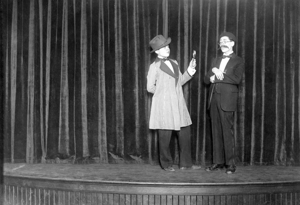 A young Orson Welles (dressed as Sherlock Holmes) holding a magnifying glass onstage next to his Todd School classmate Sherman Perlman dressed as Groucho Marx