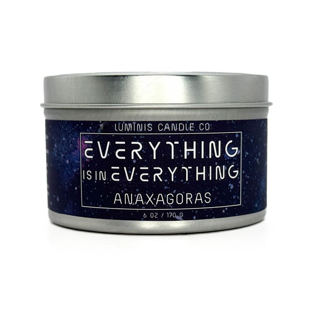 A silver candle tin. Its label has a space background and in white text reads the scent name, "Everything is in Everything," followed by its character inspiration, Anaxagoras.
