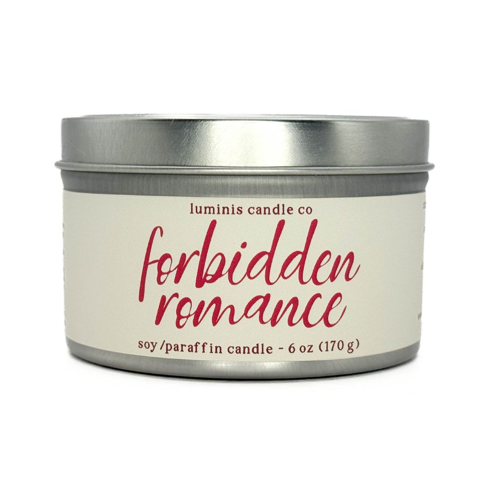 A silver candle tin with a label that reads "Forbidden Romance".