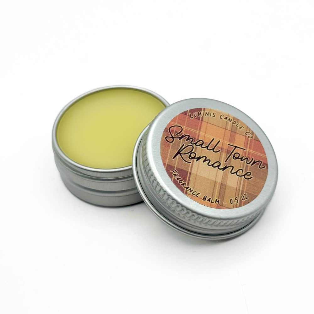 A small silver tin containing a pale yellow balm. The label on the lid reads "Small Town Romance".