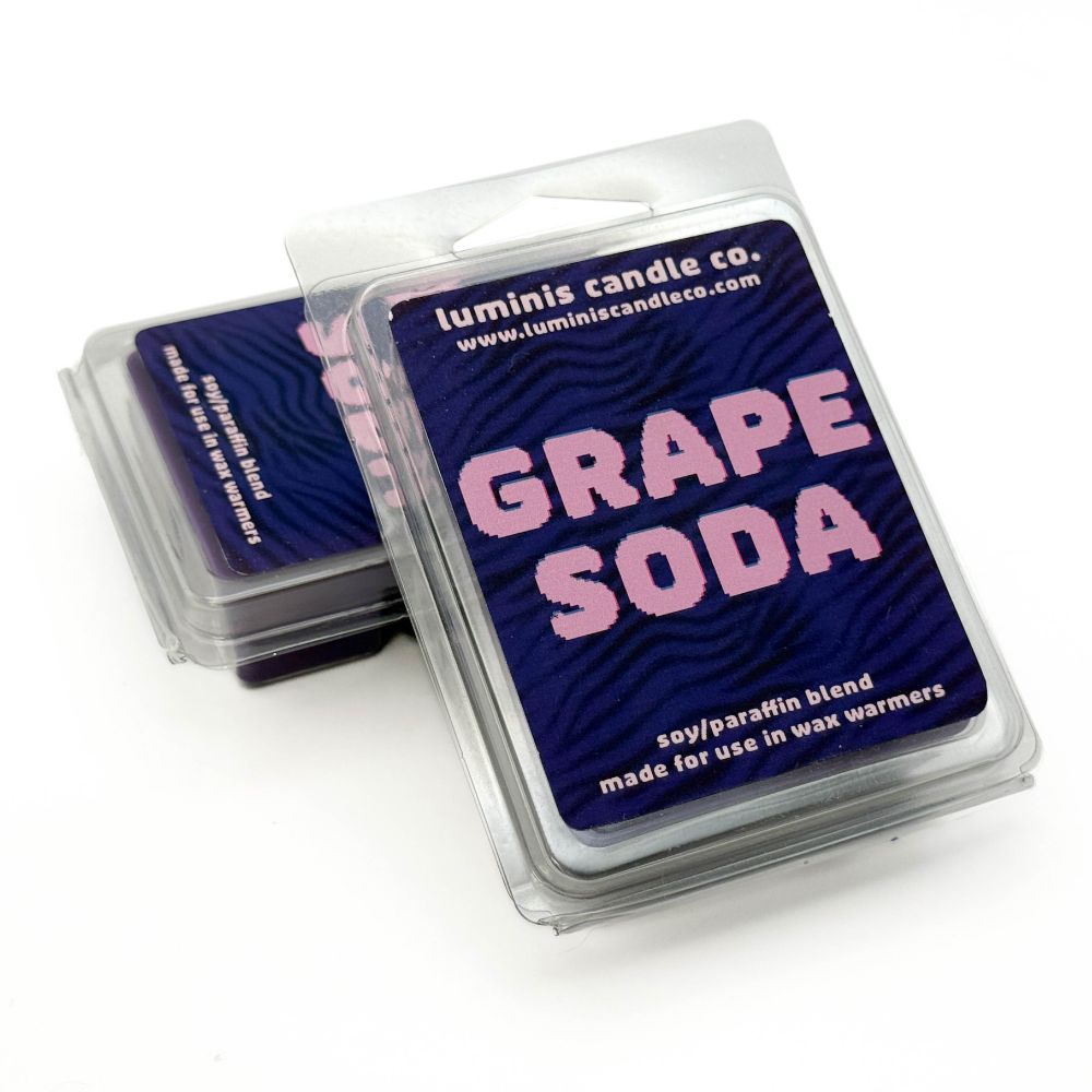 A pair of wax melts with one propped up in front of the other. The melts in front show the label, which says the scent name: "Grape Soda".
