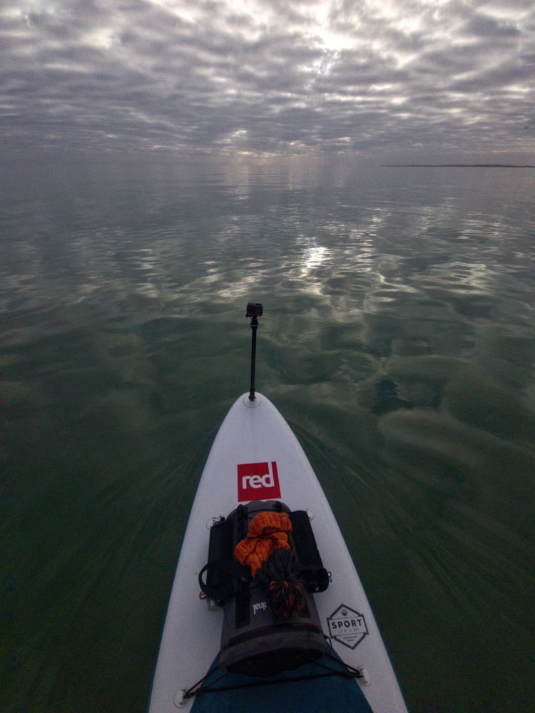 Paddleboard on a glassy sea under grey skies