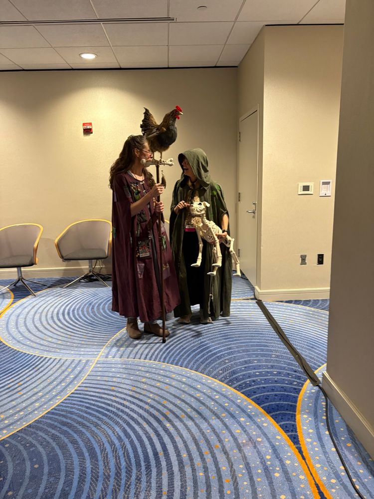 Imade of a cosplayer as the Dust Wife with a chicken on a walking stick and a bone dog.