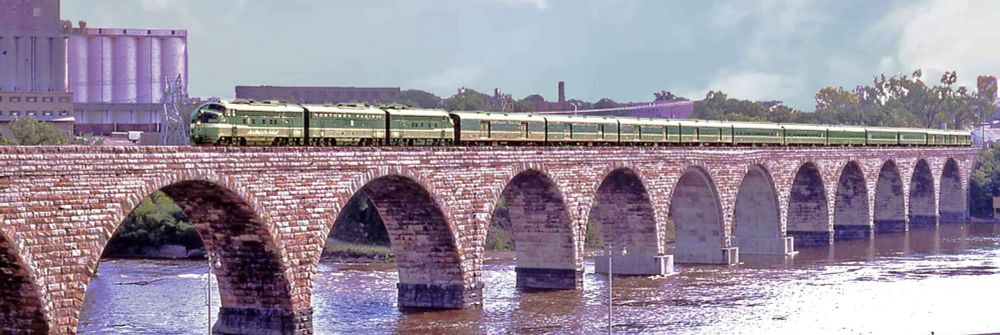 The Mainstreeter, hauled by diesels and consisting of streamlined coaches, cross the Stone Arch Bridge.