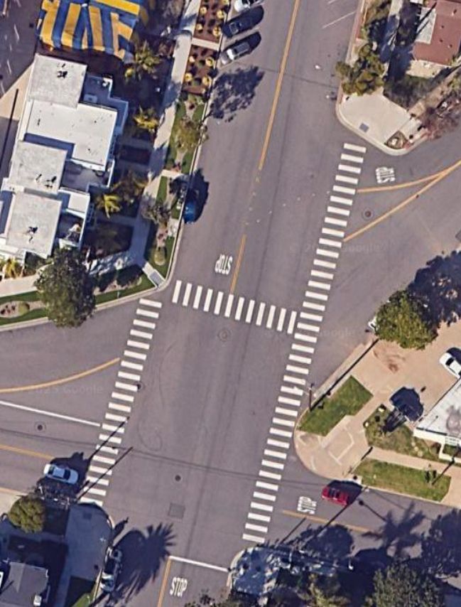 an 5 pointed traffic intersection in a residential neighborhood.
there's a crosswalk across it that looks like a backwards h