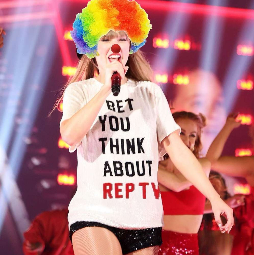 taylor from the eras tour red era. her shirt has been edited to read "I bet you think about rep tv" and she's wresting a multicolour clown wig. 