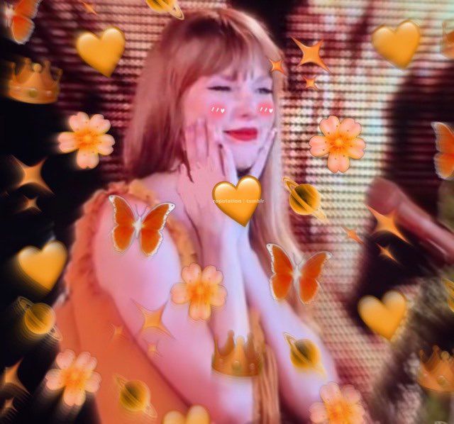 taylor swift from the eras tour, in her orange evermore dress. she's cupping her face with both hands and smiling so big and cute. edited in is an explosion of orange emoji around her of hearts, flowers, crowns, sparkles, and butterflies.
