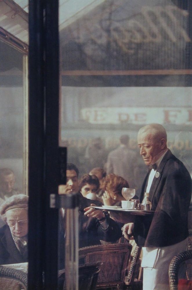 photo
shot through large glass paned doors
a waiter carrying a tray in a busy street cafe