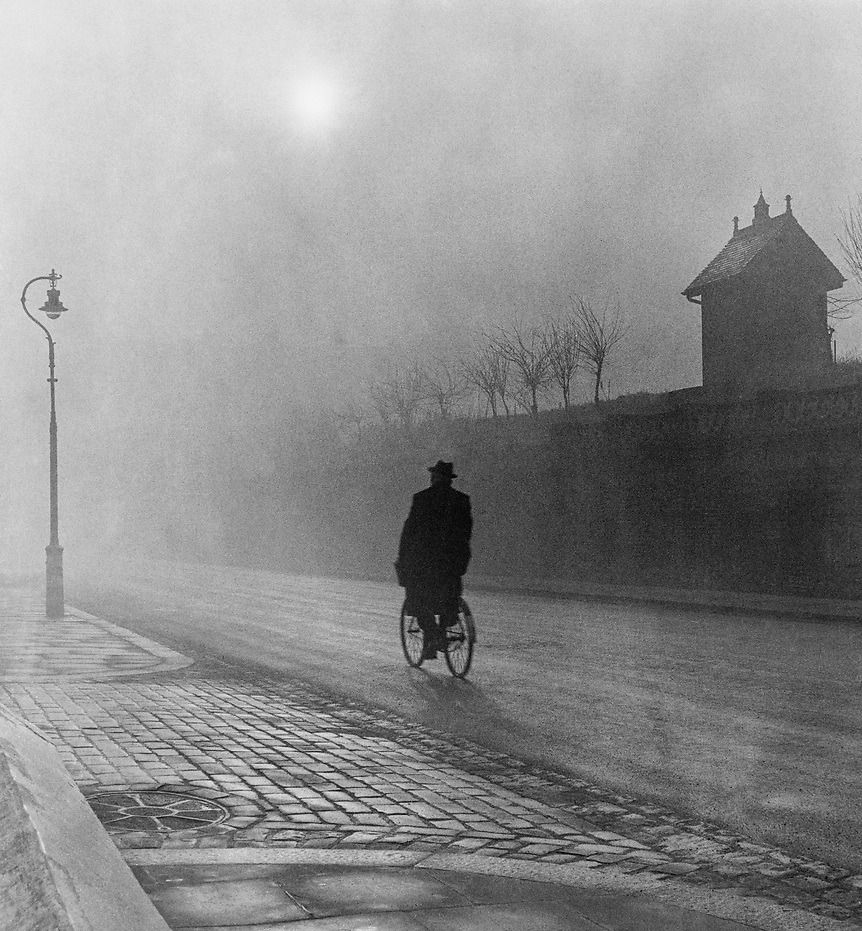 Man on bicycle in fog by Campden Hill Road water reservoir, West London, 1951 - by Bill Brandt 