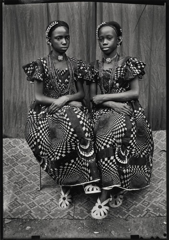 two young people posing in ornate and intricately patterned dresses