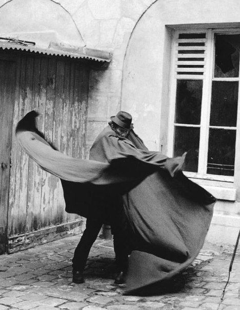 man outside, wrapping a huge cape around himself