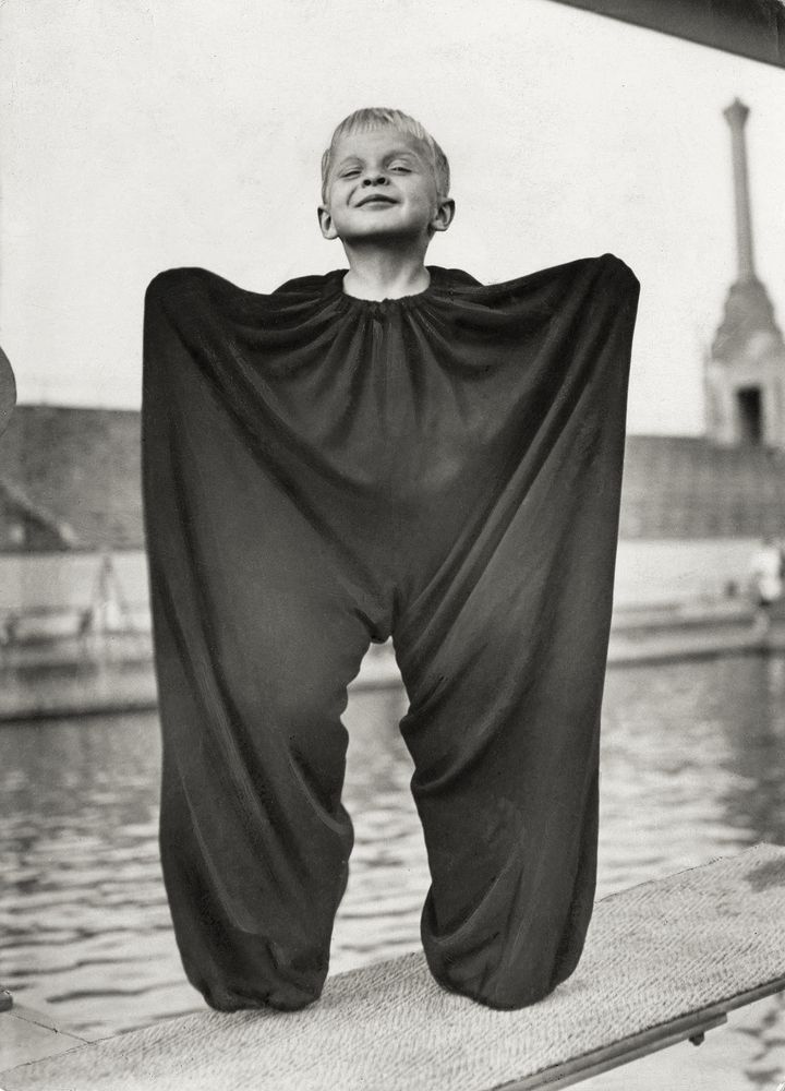 small child in a huge pair of trousers, tied up to the neck