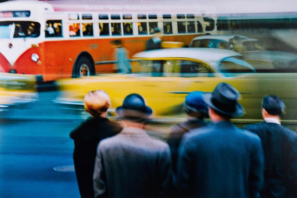 people watch traffic blur past. a large bus