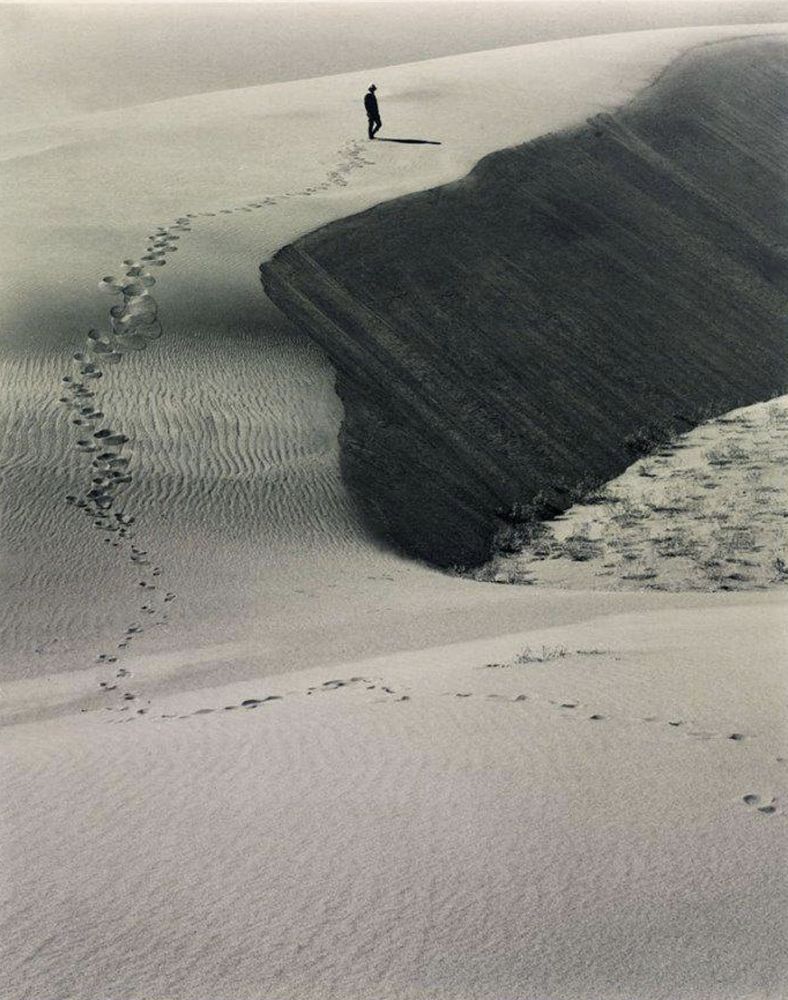 sand dunes, a solitary figure walks off leaving a trail