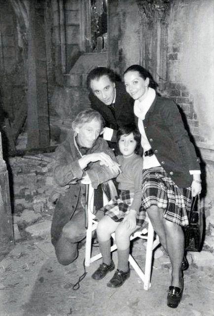 young child sat in a chair surrounded by adults