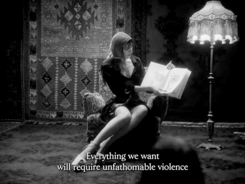 woman sat in chair holding a book 'everything we want will require unfathomable violence'