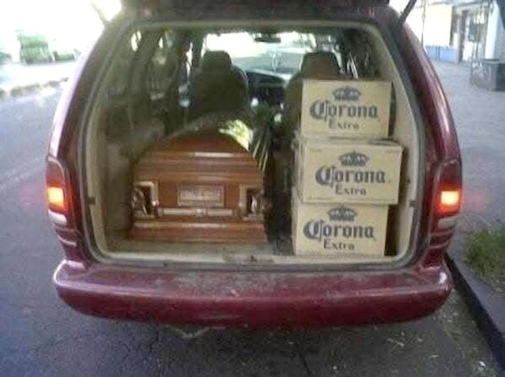 back of a car. inside is a coffin and a few crates of beer.