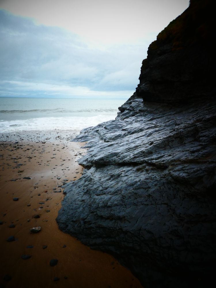 view of a rock face. behind is the irish sea