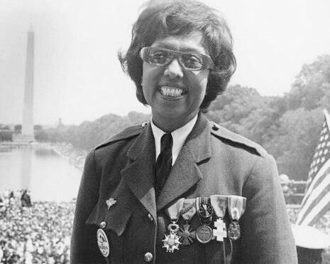 a smiling woman wearing a chest full of medals.