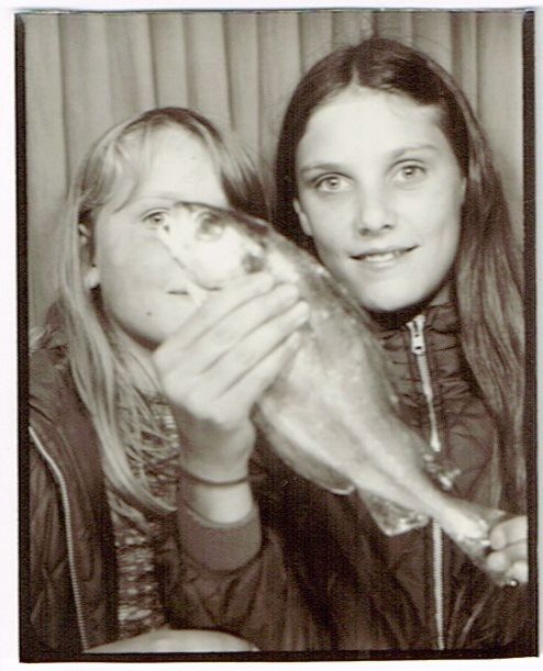 Two girls in photo both, one is holding a fish