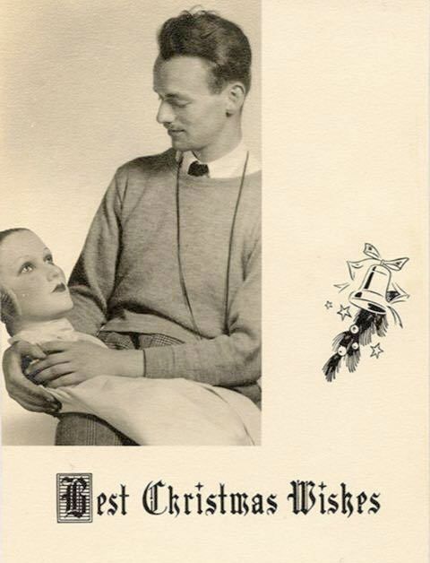 man looking lovingly at a mannequin head, held on his lap
best xmas wishes