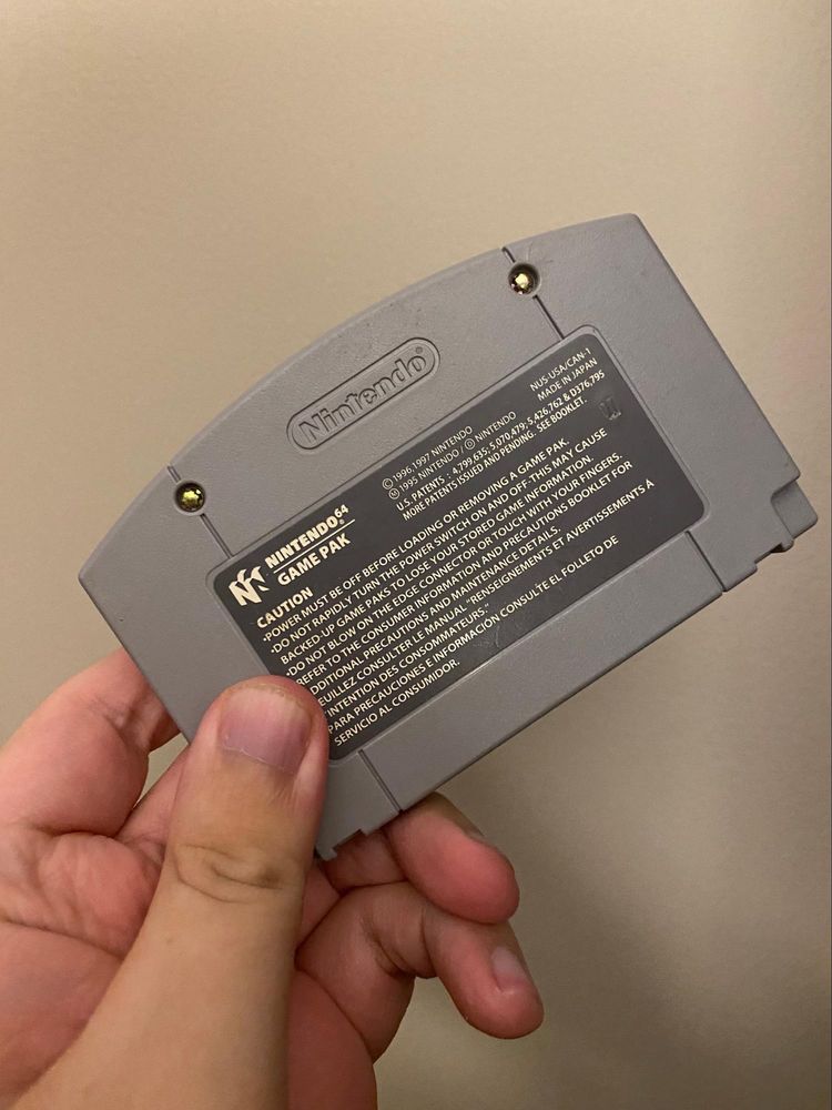 Photograph of a hand holding a Nintendo 64 cartridge.