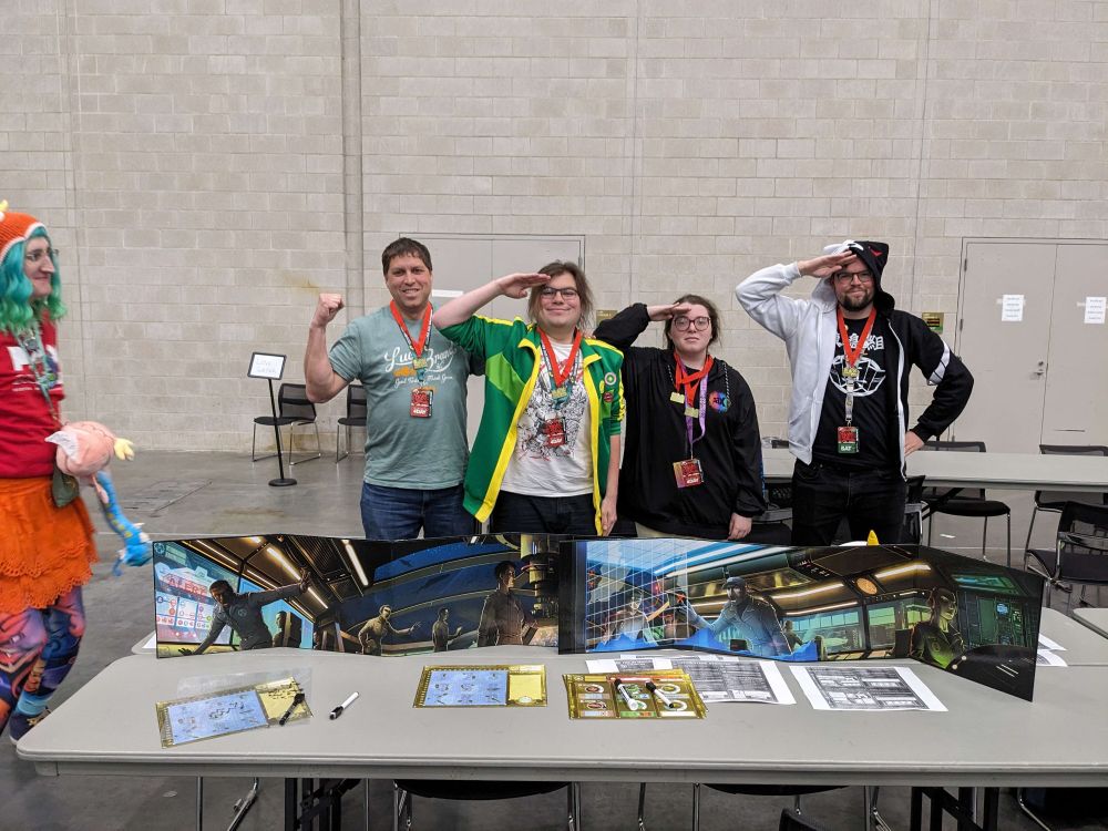 Winners of the Saturday Night Showdown tournament at PAX East 2025, posing with medals, and a copy of the finals game, Captain Sonar