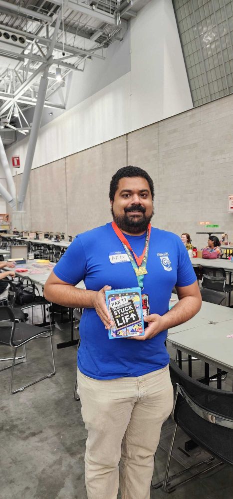 Attendee of PAX East 2025 posing with board game (I'm Stuck in a Lift) and medal, for winning the Thursday Night Throwdown