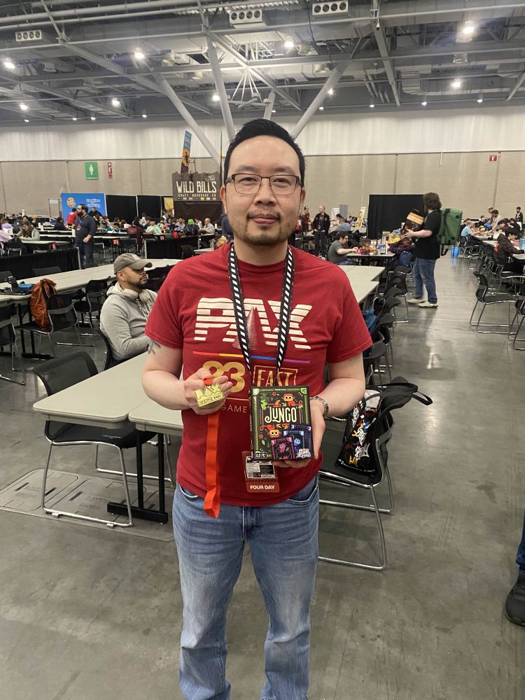 A PAX East 2025 attendee holding a medal and card game 