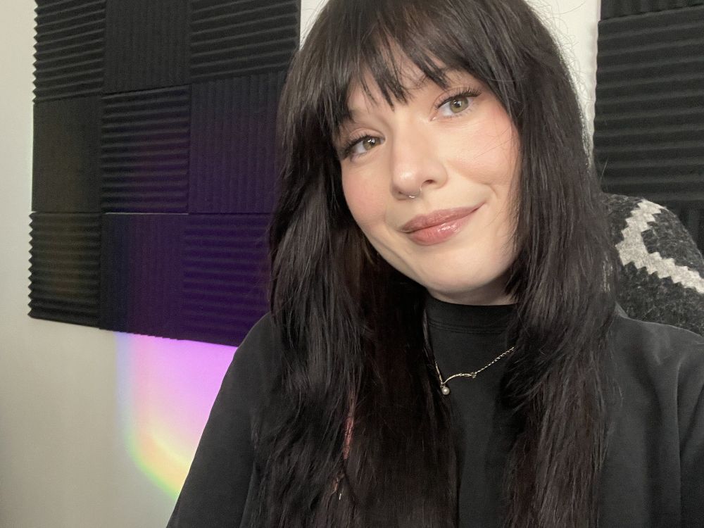 Photo of streamer @marinahascoffee. There are black foam acoustic panels on the wall behind her. 
