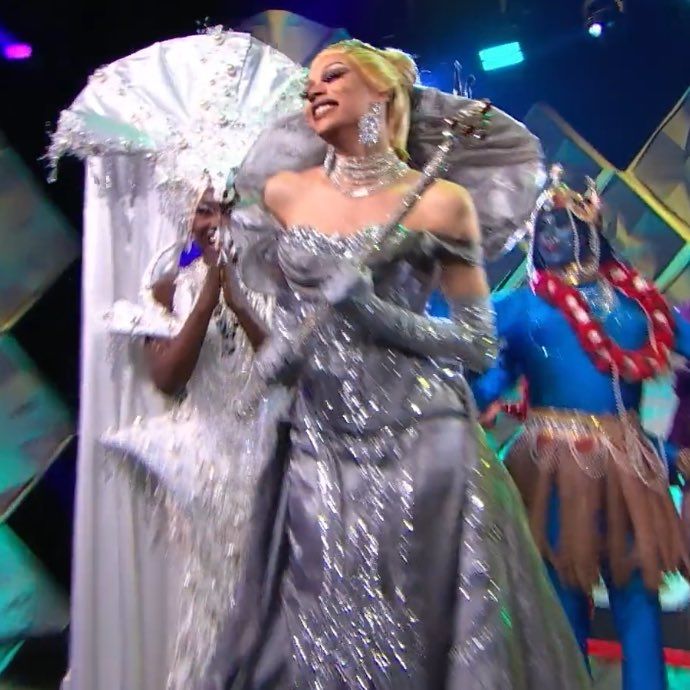Virgo Queen in a silver gown, holding her winning scepter on the stage of Canada's Drag Race and smiling