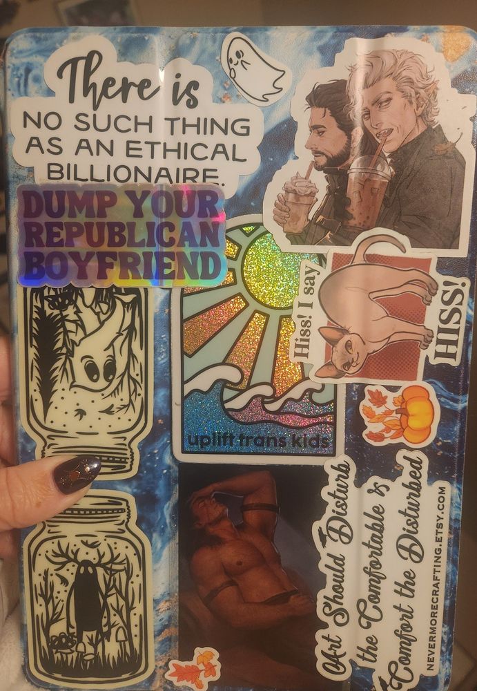 Tablet covered in random stickers. Some cryptid stickers and BG3 stickers. Some have text that reads, "Dump your republican boyfriend," "uplift trans kids," and "There is no such thing as an ethical billionaire." 